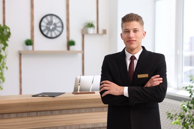 Photo of Portrait of smiling receptionist with crossed arms in hotel
