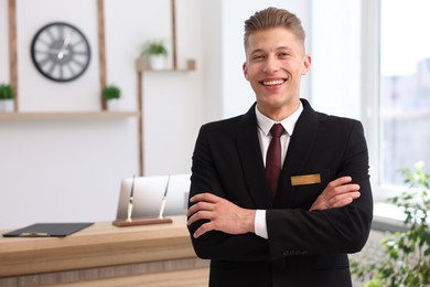 Photo of Portrait of smiling receptionist with crossed arms in hotel