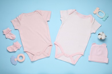 Photo of Baby clothes, cotton flower and accessories on light blue background, flat lay