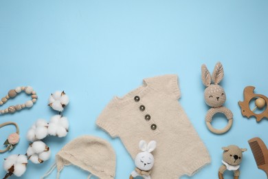 Photo of Baby clothes, cotton flowers and accessories on light blue background, flat lay. Space for text
