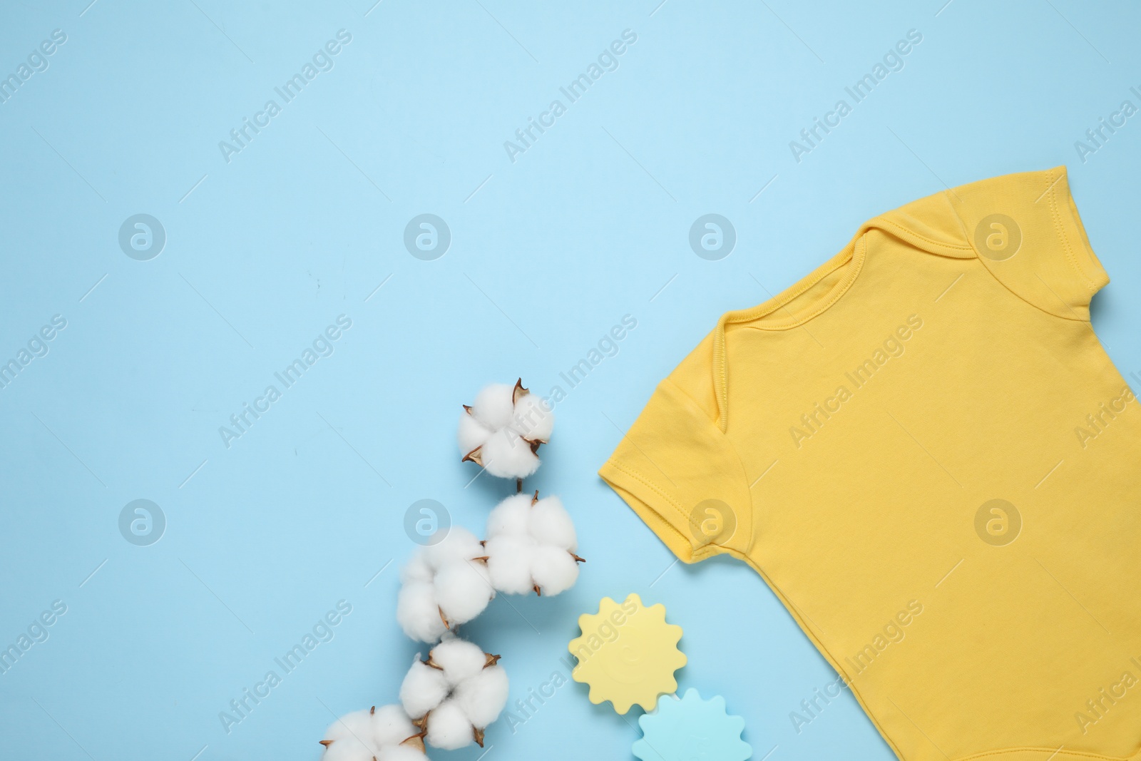 Baby clothes, cotton flowers and accessories on light blue background, flat lay. Space for text Photo of Baby clothes, cotton flowers and accessories on light blue background, flat lay. Space for text