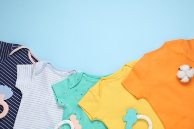 Photo of Baby clothes, cotton flower and accessories on light blue background, flat lay. Space for text