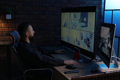 Photo of Security guard monitoring CCTV cameras in office at night