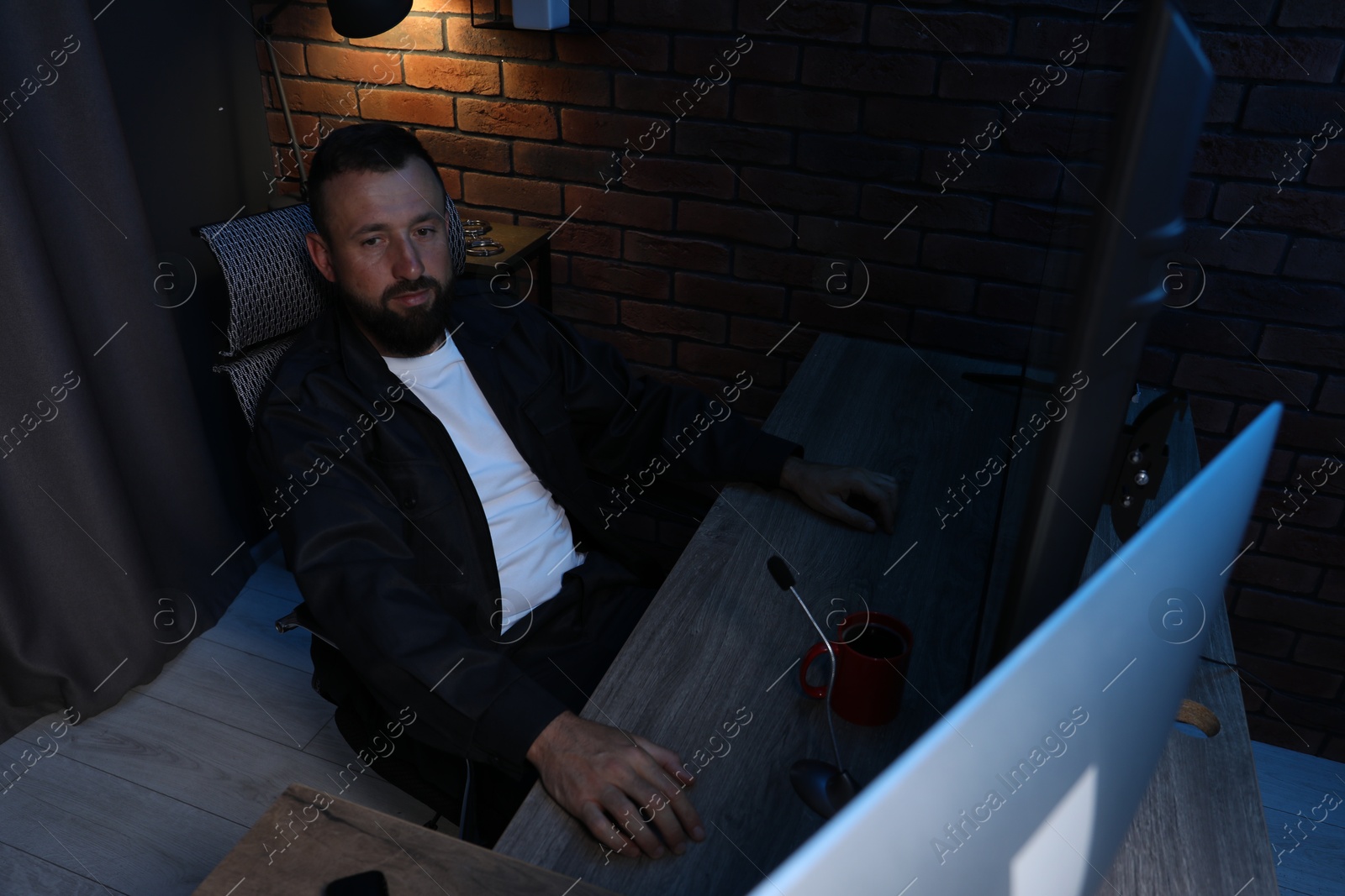 Photo of Security guard monitoring CCTV cameras in office at night