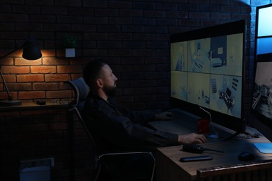 Photo of Security guard monitoring CCTV cameras in office at night