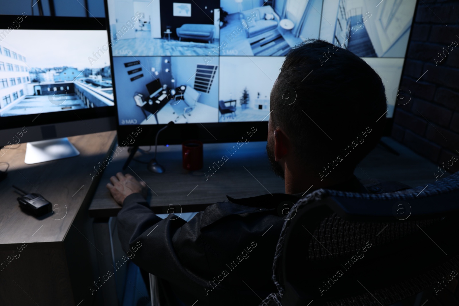 Security guard monitoring CCTV cameras in office at night, back view Photo of Security guard monitoring CCTV cameras in office at night, back view