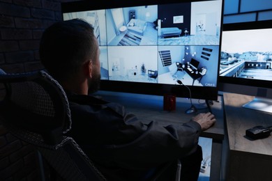 Photo of Security guard monitoring CCTV cameras in office at night, back view