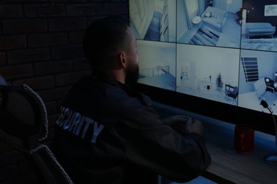 Photo of Security guard monitoring CCTV cameras in office at night