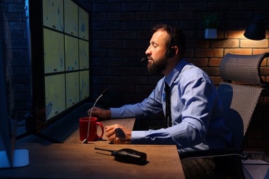 Photo of Security guard monitoring CCTV cameras in office at night