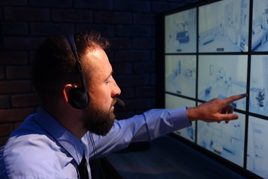 Photo of Security guard monitoring CCTV cameras in office at night