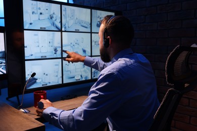 Photo of Security guard monitoring CCTV cameras in office at night