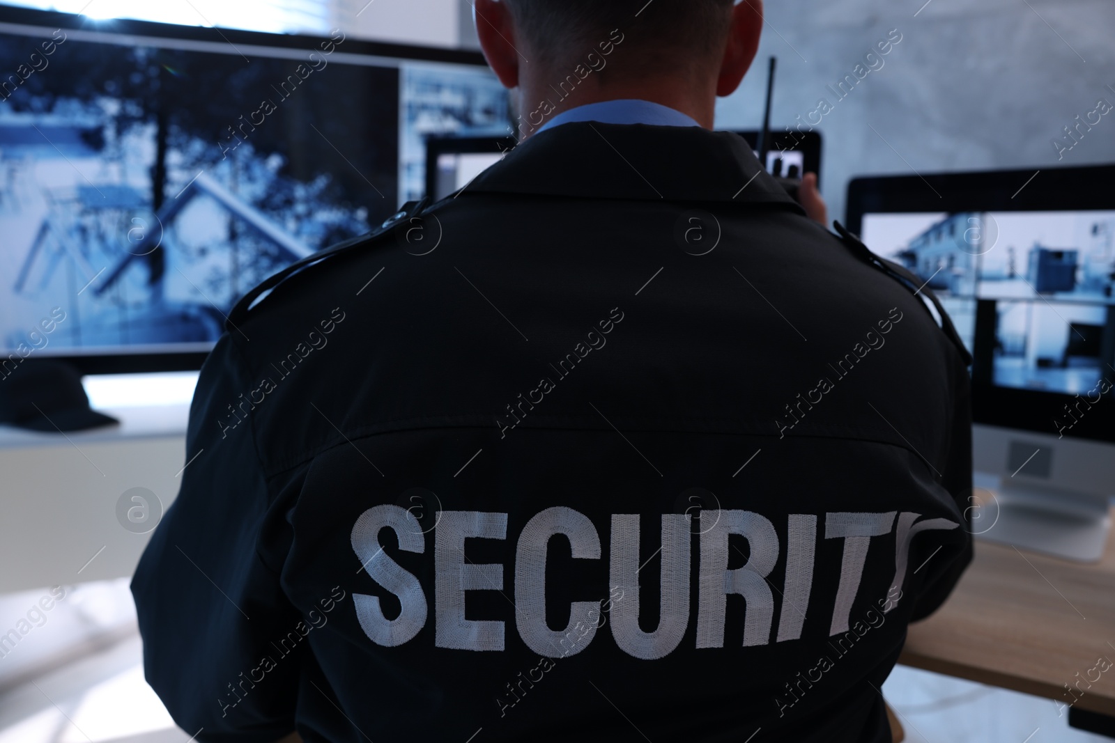 Security guard monitoring CCTV cameras in office, back view Photo of Security guard monitoring CCTV cameras in office, back view