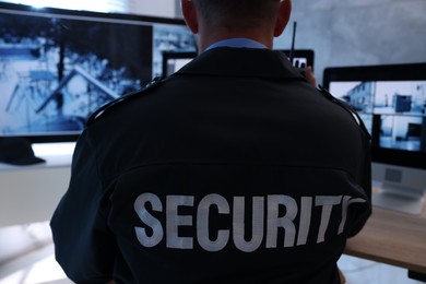 Photo of Security guard monitoring CCTV cameras in office, back view