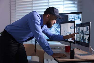 Photo of Security guard monitoring CCTV cameras in office