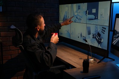 Photo of Security guard monitoring CCTV cameras in office at night