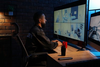 Photo of Security guard monitoring CCTV cameras in office at night