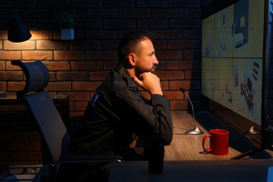 Photo of Security guard monitoring CCTV cameras in office at night
