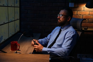 Photo of Security guard monitoring CCTV cameras in office at night