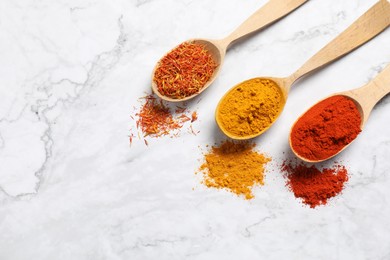 Photo of Different aromatic spices in spoons on white marble table, flat lay. Space for text
