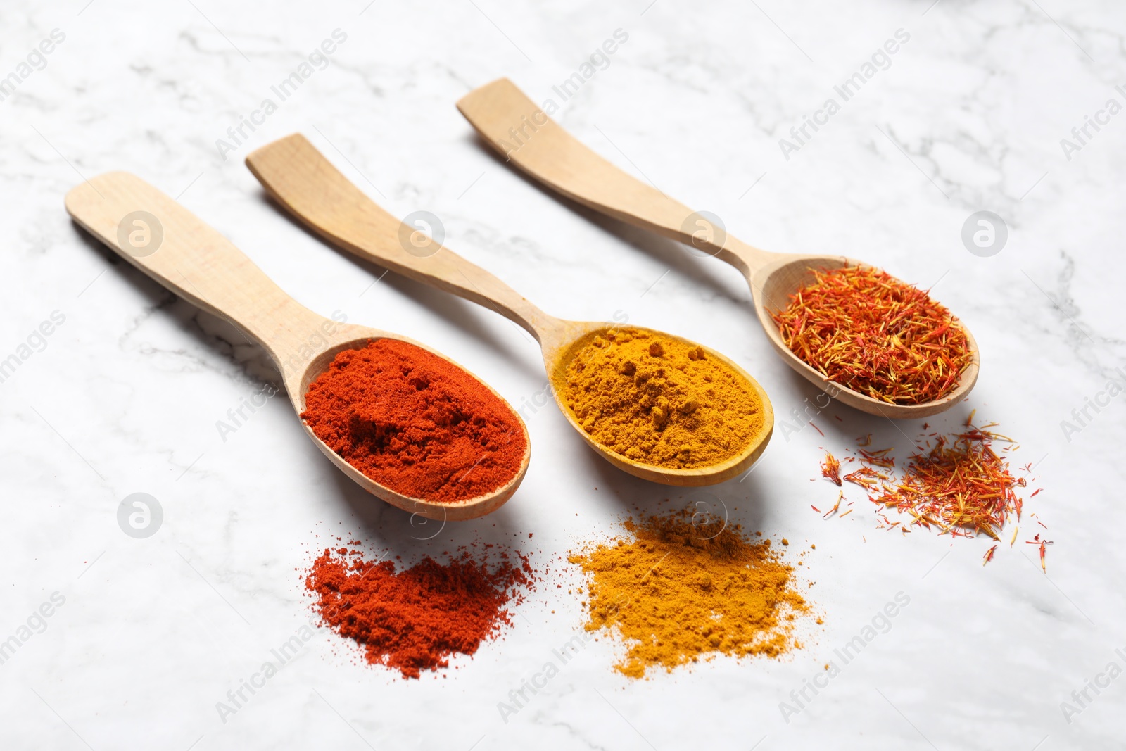 Different aromatic spices in wooden spoons on white marble table, closeup Photo of Different aromatic spices in wooden spoons on white marble table, closeup