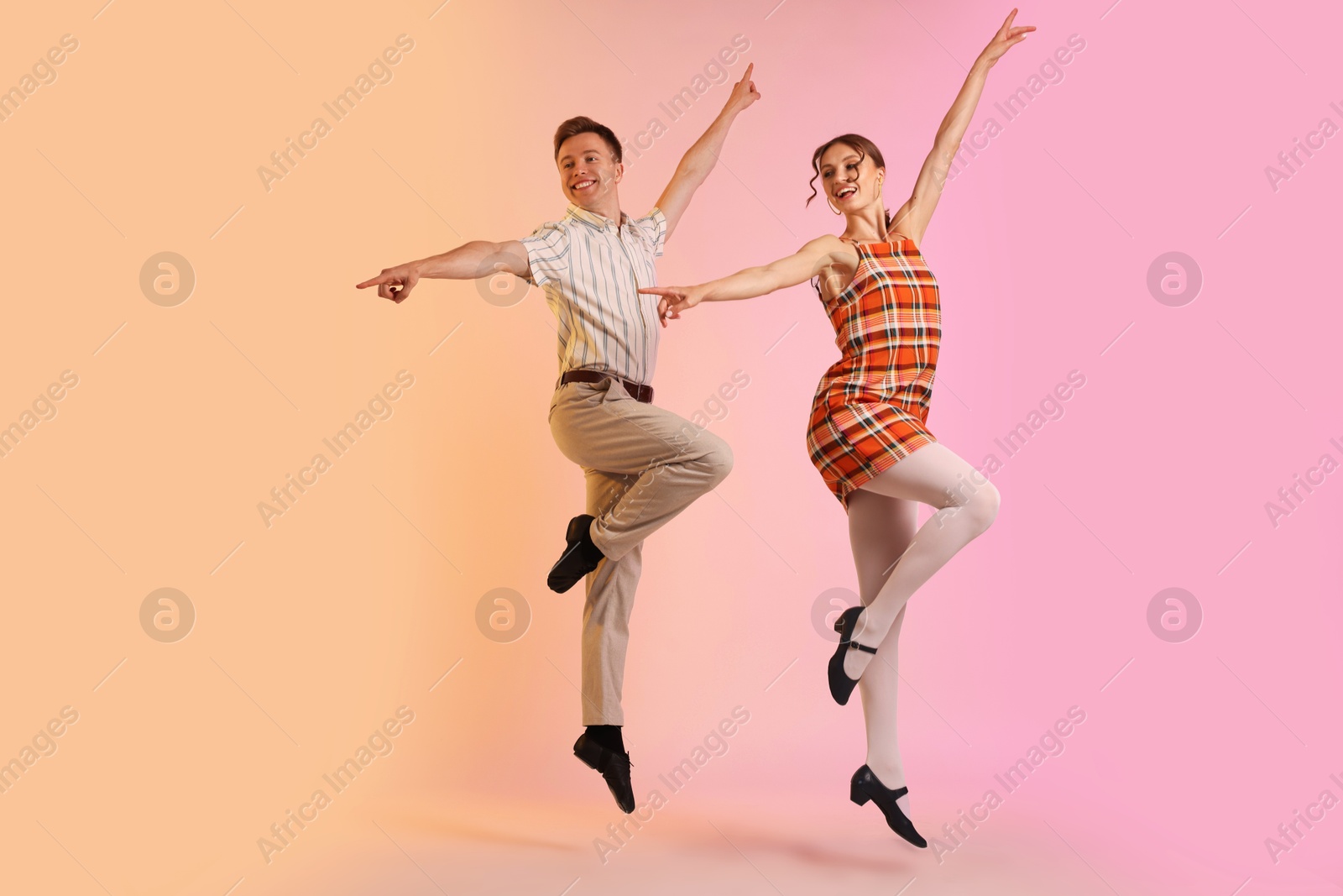 Photo of Happy couple in retro outfits dancing on color background