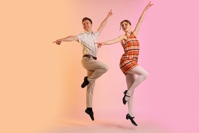 Photo of Happy couple in retro outfits dancing on color background