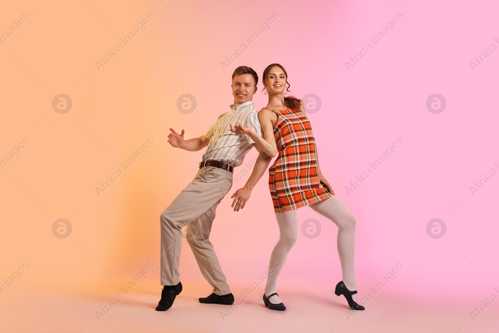 Happy couple in retro outfits dancing on color background Photo of Happy couple in retro outfits dancing on color background