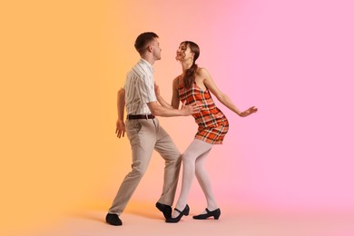 Photo of Happy couple in retro outfits dancing on color background
