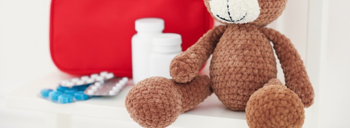 Photo of Pediatrics concept. Toy bear with pills on white background, closeup