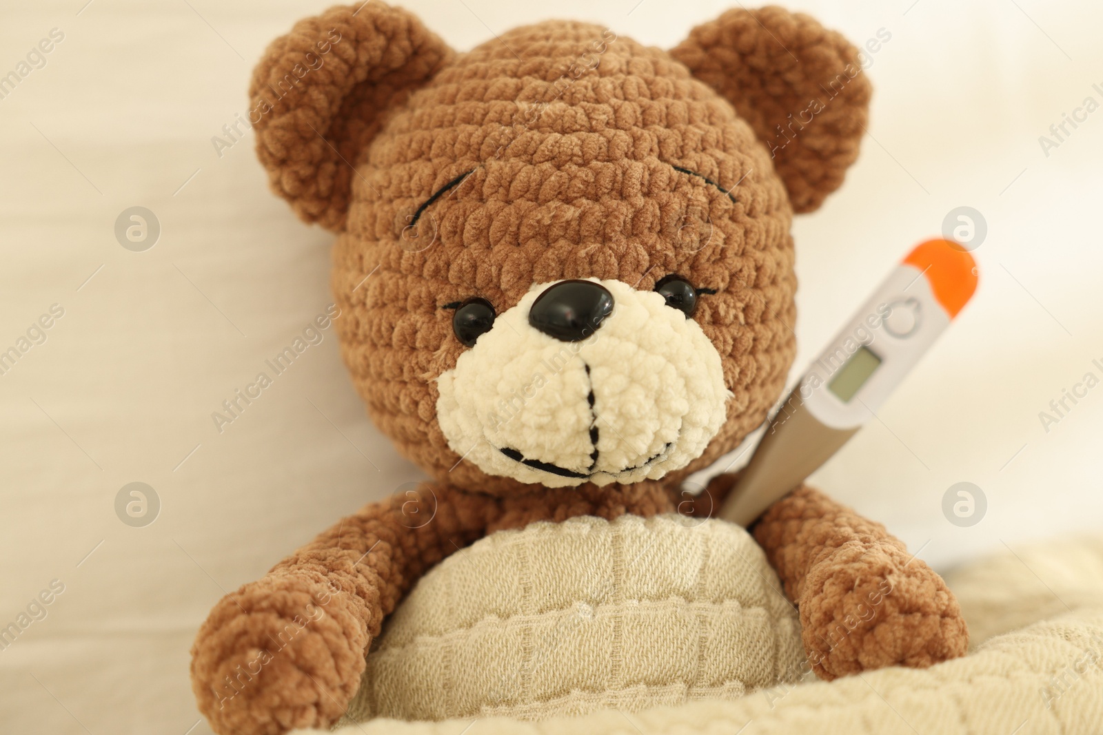 Pediatrics concept. Toy bear with thermometer in bed, closeup Photo of Pediatrics concept. Toy bear with thermometer in bed, closeup