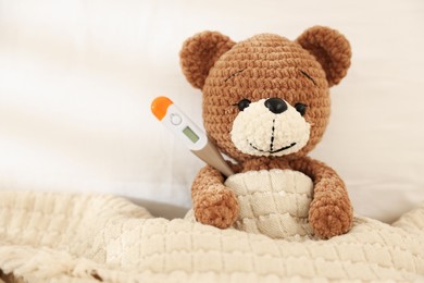Photo of Pediatrics concept. Toy bear with thermometer in bed, space for text