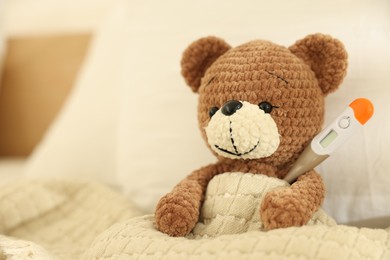 Photo of Pediatrics concept. Toy bear with thermometer in bed, space for text