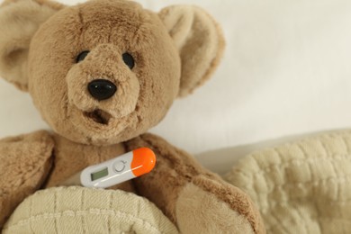 Photo of Pediatrics concept. Toy bear with thermometer in bed, closeup. Space for text