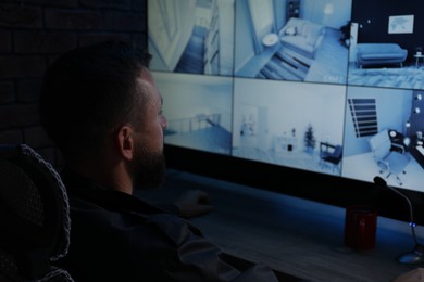 Photo of Security guard monitoring CCTV cameras in office at night