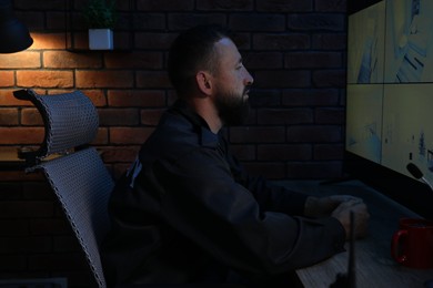 Photo of Security guard monitoring CCTV cameras in office at night