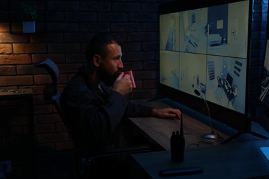 Photo of Security guard monitoring CCTV cameras in office at night