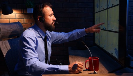 Photo of Security guard monitoring CCTV cameras in office at night