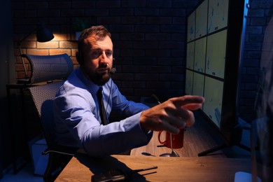 Photo of Security guard monitoring CCTV cameras in office at night