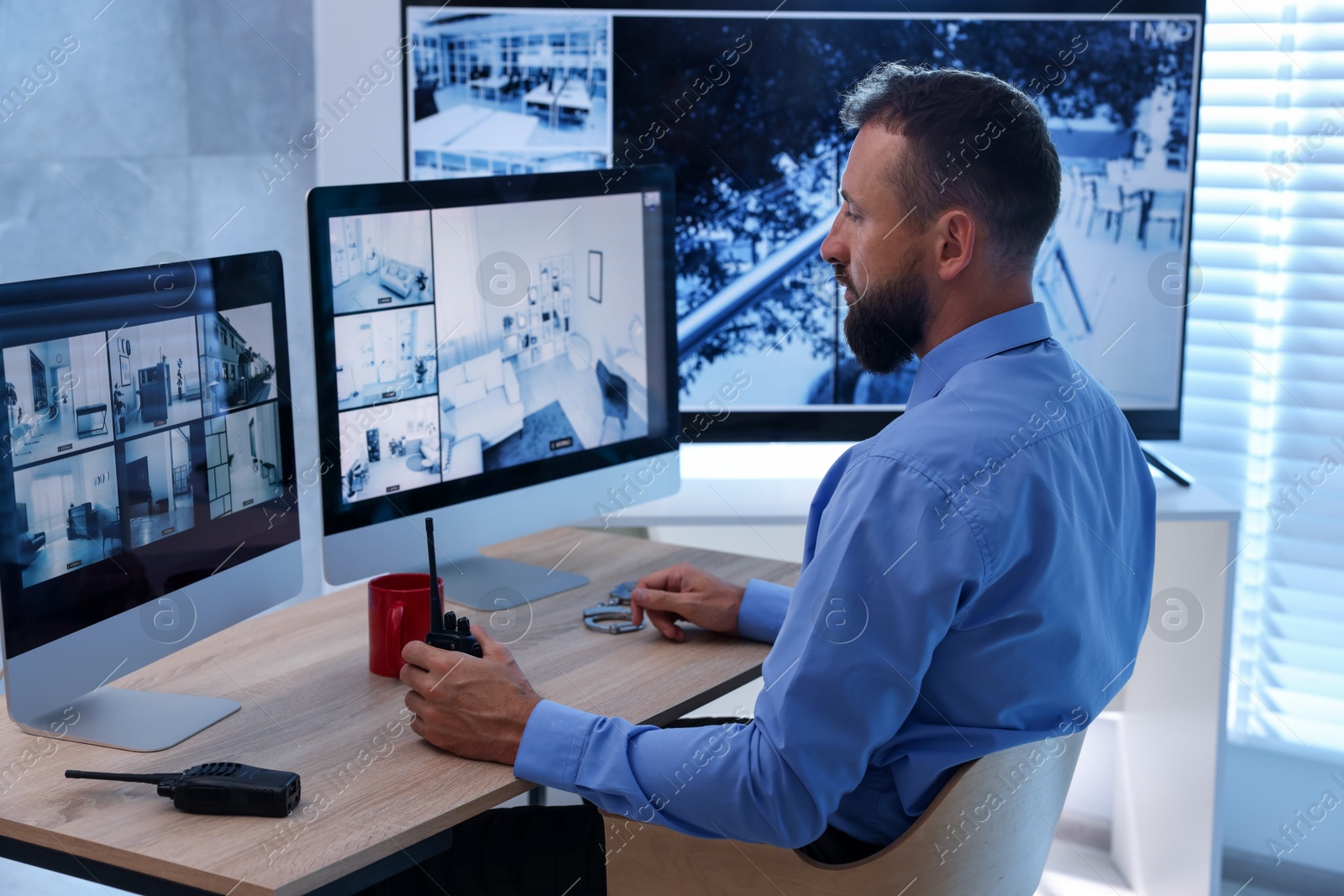 Photo of Security guard monitoring CCTV cameras in office