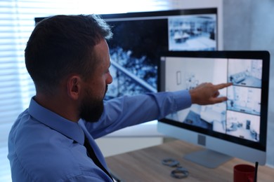 Photo of Security guard monitoring CCTV cameras in office