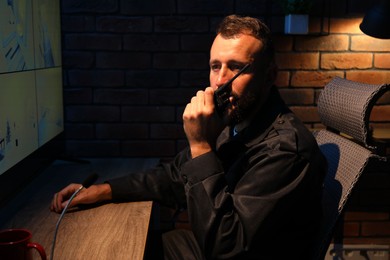Photo of Security guard monitoring CCTV cameras and using walkie talkie in office at night