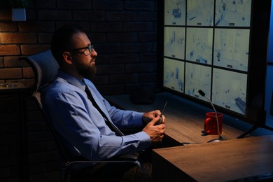 Photo of Security guard monitoring CCTV cameras in office at night
