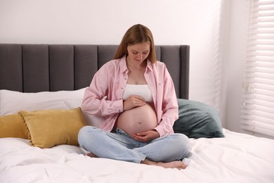Photo of Beautiful pregnant woman on bed at home