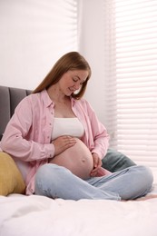 Photo of Beautiful pregnant woman on bed at home