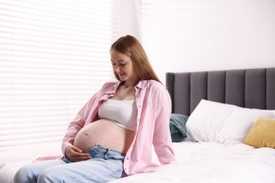 Photo of Beautiful pregnant woman on bed at home