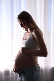 Photo of Beautiful pregnant woman near window at home