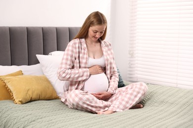 Photo of Beautiful pregnant woman on bed at home