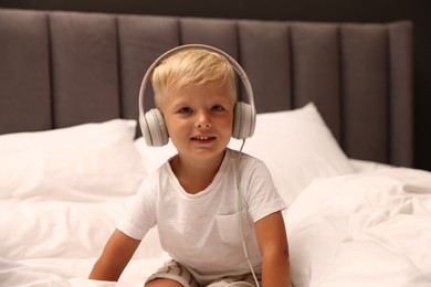 Photo of Cute little boy in headphones on bed