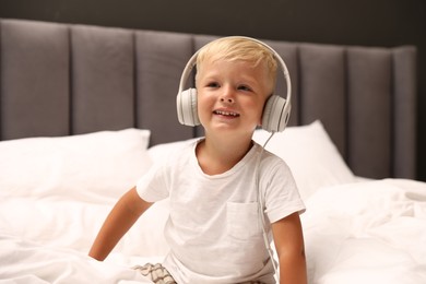 Photo of Cute little boy in headphones on bed