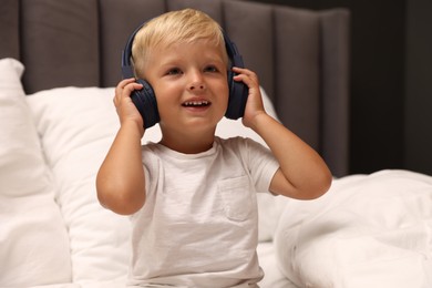 Photo of Cute little boy in headphones on bed